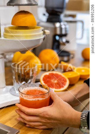 Woman hands with whole and half fresh ripe oranges and grapefruits cooking detox juice on table Woman hands with whole and half fresh ripe oranges and grapefruits cooking detox juice on table 86991206