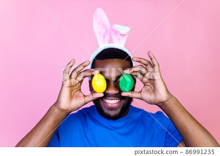 happy young brazil man with bunny ears in studio pink wall background 86991235