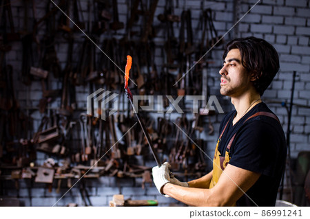 italian brunette man blacksmith working in the workshop 86991241
