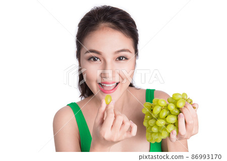 Young beautiful asian woman eating fresh grapes isolated on white background 86993170
