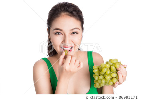 Young beautiful asian woman eating fresh grapes isolated on white background. 86993171