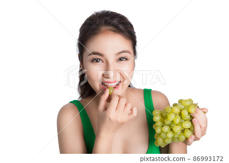 Young beautiful asian woman eating fresh grapes isolated on white background 86993172