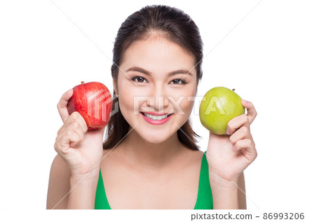 Attractive smiling young asian woman holding green apple isolated over white background. 86993206
