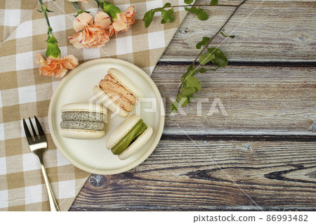 Decorative flowers and macarons on a wooden table Decorative flowers and macarons on a wooden table 86993482