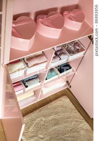 Closeup shelves pink female childish closet with neatly folded clothes Marie Kondo vertical storage Closeup shelves pink female childish closet with neatly folded clothes Marie Kondo vertical storage 86993956