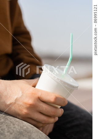 Close-up of male hand holding a paper coffee cup Close-up of male hand holding a paper coffee cup 86995121