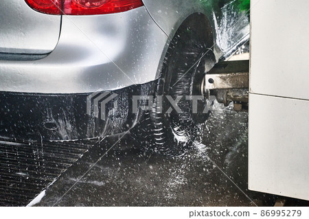 Wheel scrub brush in action at automatic car wash service Wheel scrub brush in action at automatic car wash service 86995279