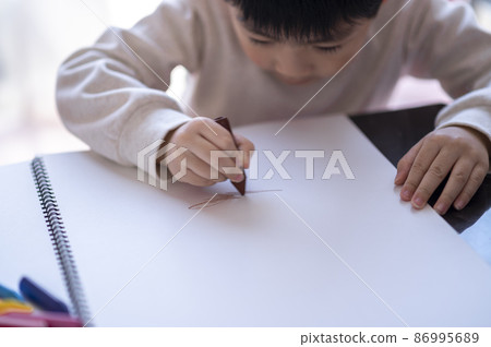 一個 4 歲的男孩用蠟筆在速寫本上畫畫 一個 4 歲的男孩用蠟筆在速寫本上畫畫 86995689