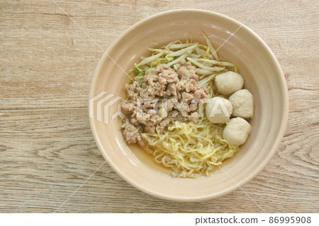 Chinese egg yellow noodles topping boiled chop pork and ball in soup on bowl 86995908