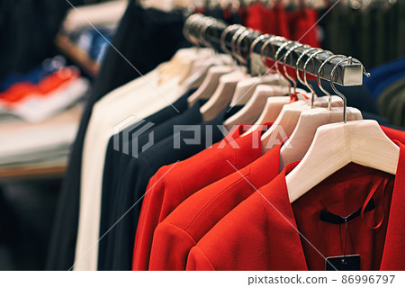 Woman jackets in red, blue, white and other colors on hangers in a retail clothes store. Woman jackets in red, blue, white and other colors on hangers in a retail clothes store. 86996797