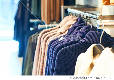 Woman pullover sweaters in different colors on hangers in a retail clothes store. Woman pullover sweaters in different colors on hangers in a retail clothes store. 86996809