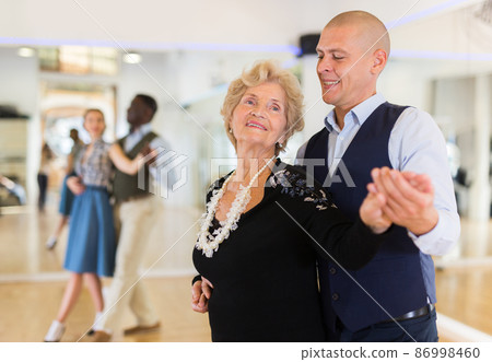 Man and senior woman dancing waltz in studio Man and senior woman dancing waltz in studio 86998460