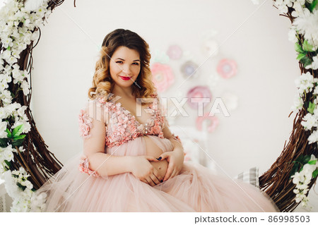 Pregnant woman sitting on big decorated vine Pregnant woman sitting on big decorated vine 86998503