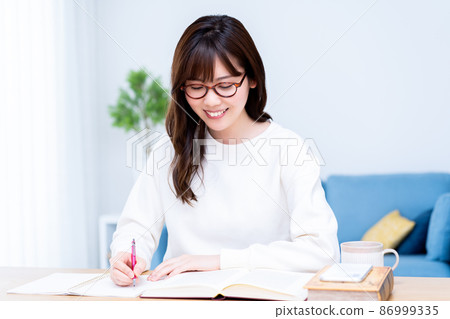 Woman with glasses studying in the living room 86999335
