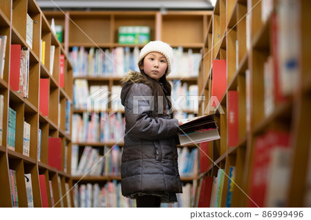 Girl choosing a book in the library Girl choosing a book in the library 86999496