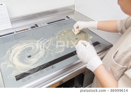 Elementary school kid helping clean a dirty IH stove 86999614
