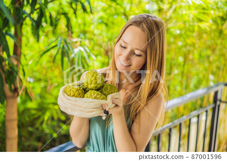 Cherimoya in a reusable bag in female hands. Zero waste concept, plastic free concept. Healthy clean eating diet and detox. Summer fruits 87001596