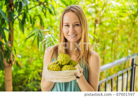 Cherimoya in a reusable bag in female hands. Zero waste concept, plastic free concept. Healthy clean eating diet and detox. Summer fruits 87001597