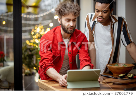 Two guys watching movie together on digital tablet at home Two guys watching movie together on digital tablet at home 87001779