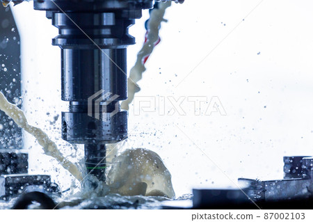 Close-up view of vertical cnc steel milling process with external water coolant streams, splashes and a lot of metal chips, high contrast Close-up view of vertical cnc steel milling process with external water coolant streams, splashes and a lot of metal chips, high contrast 87002103