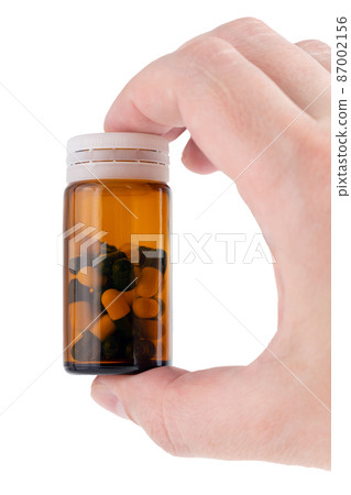 caucasian hand holding brown glass bottle with medical pills inside 87002156