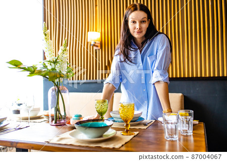 Portrait of one young beautiful caucasian woman washing a dishes and table setting daylight Portrait of one young beautiful caucasian woman washing a dishes and table setting daylight 87004067