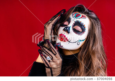 woman with painted skull on her face for Mexico D a de Muertos Mexican traditional ritual in red studio background woman with painted skull on her face for Mexico D a de Muertos Mexican traditional ritual in red studio background 87004098