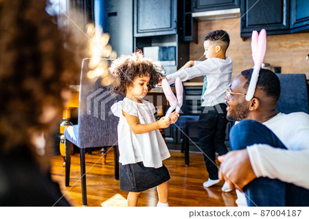 multicultural hispanic family wearing rabbit ears in living room soft sun day light 87004187