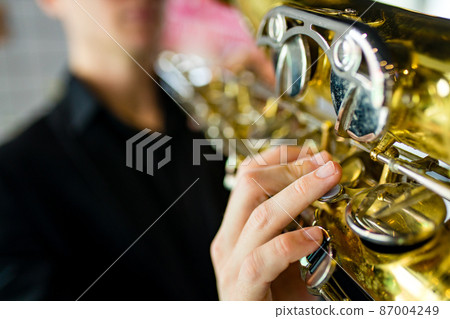 saxophone in hands close-up man in black outfit 87004249