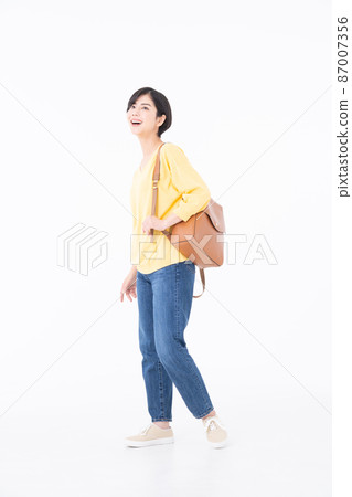 A young woman walking on a white background with her whole body 87007356