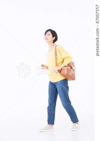 A young woman walking on a white background with her whole body 87007357