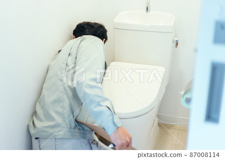 一個穿著工作服的男人正在檢查廁所 一個穿著工作服的男人正在檢查廁所 87008114