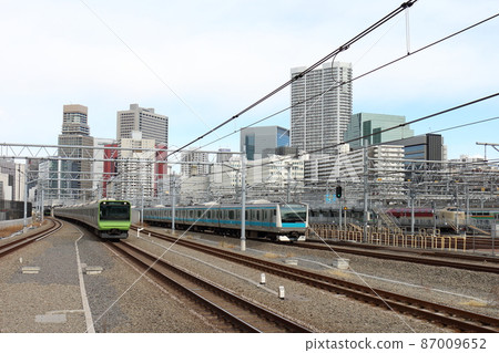 Yamanote Line E235 series train and Keihin Tohoku Line E233 series sleeper limited express "Sunrise Seto / Izumo" at Takanawa Gateway Station 87009652