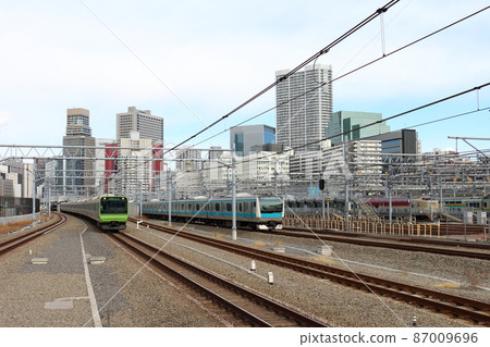 Yamanote Line E235 series train and Keihin Tohoku Line E233 series at Takanawa Gateway Station, sleeper limited express "Sunrise Seto / Izumo" 87009696