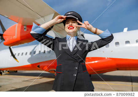 Cheerful woman flight attendant standing outdoors at airport 87009982