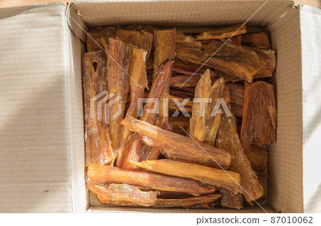 Chew Pet treats in a cardboard box. Dried beef tendons. Pieces of a natural, healthy dog treat to help clean teeth from tartar. Selective Focus Chew Pet treats in a cardboard box. Dried beef tendons. Pieces of a natural, healthy dog treat to help clean teeth from tartar. Selective Focus 87010062