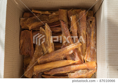 Chew Pet treats in a cardboard box. Dried beef tendons. Pieces of a natural, healthy dog treat to help clean teeth from tartar. Selective Focus Chew Pet treats in a cardboard box. Dried beef tendons. Pieces of a natural, healthy dog treat to help clean teeth from tartar. Selective Focus 87010066