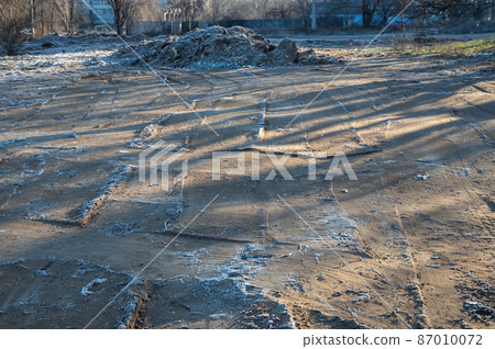 Frozen ground leveled by a bulldozer. The top layer of soil is covered with frost. Construction site, industry. 87010072
