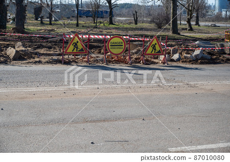 Place of repair and road works. Wooden fence with three signs. The barrier red and white tape. Daytime. Place of repair and road works. Wooden fence with three signs. The barrier red and white tape. Daytime. 87010080