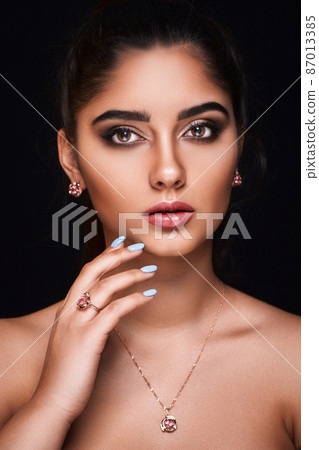 portrait of Indian woman who advertises luxury jewelry isolated on dark background. Jewelry concept portrait of Indian woman who advertises luxury jewelry isolated on dark background. Jewelry concept 87013385