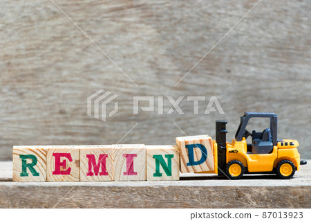 Toy forklift hold letter block d to complete word remind on wood background 87013923