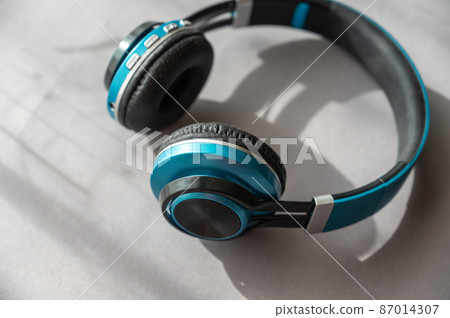 Turquoise and black headphones against a gray background. Wireless device for listening to music and communication. 87014307