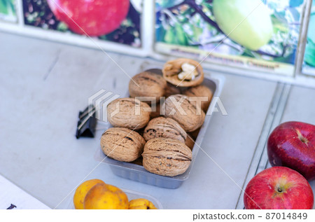 Agricultural industry. Street trade. Traditional fair. Giant walnuts on the counter. Ripe apples and yellow eggs lie side by side. Daytime. Selective focus. 87014849
