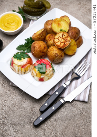Portion of delicious chicken aspic and baked potato on a plate on concrete table Portion of delicious chicken aspic and baked potato on a plate on concrete table 87015441