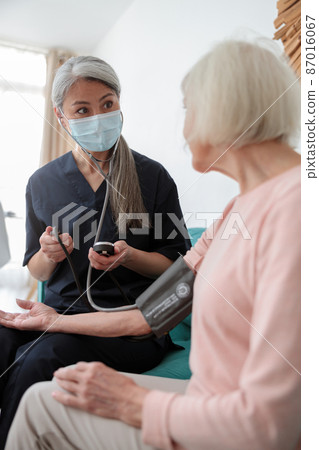 Medical worker examining elderly female at home Medical worker examining elderly female at home 87016067