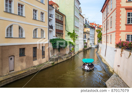Certovka, cruise boat with tourists sailing between buildings on water canal in Lesser Town, Prague, Czech Republic Certovka, cruise boat with tourists sailing between buildings on water canal in Lesser Town, Prague, Czech Republic 87017079