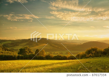 Sunset over hilly landscape, the golden glow of the setting sun 87017334