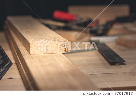 A man makes wood products with the help of special tools. Portrait of a young carpenter at work. Employment in the woodworking industry 87017917