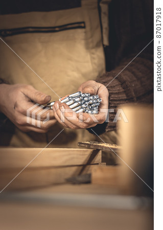 A man makes wood products with the help of special tools. Portrait of a young carpenter at work. Employment in the woodworking industry A man makes wood products with the help of special tools. Portrait of a young carpenter at work. Employment in the woodworking industry 87017918