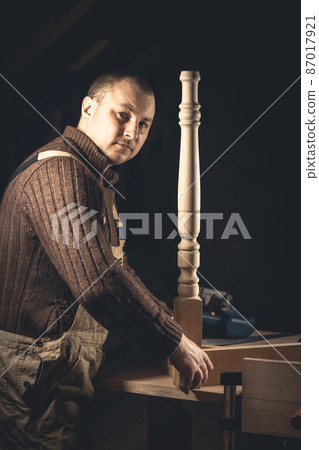 A man makes wood products with the help of special tools. Portrait of a young carpenter at work. Employment in the woodworking industry A man makes wood products with the help of special tools. Portrait of a young carpenter at work. Employment in the woodworking industry 87017921